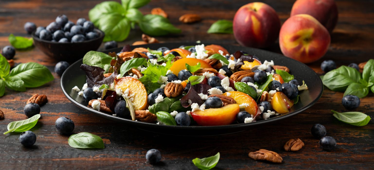 Peach, blueberry salad with vegetables, feta cheese and pecan nuts. Healthy summer food.