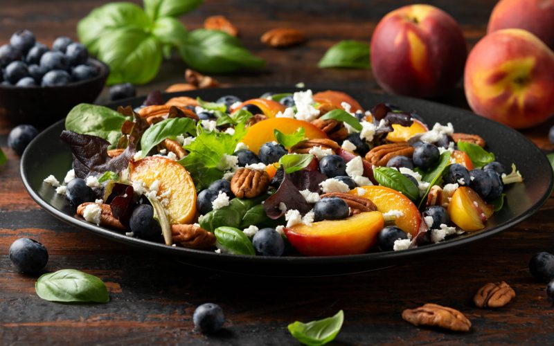 Peach, blueberry salad with vegetables, feta cheese and pecan nuts. Healthy summer food.